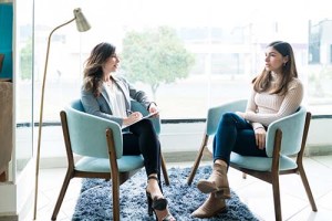 a woman patient sits in a chair across from her therapist while in the patients drug rehab program